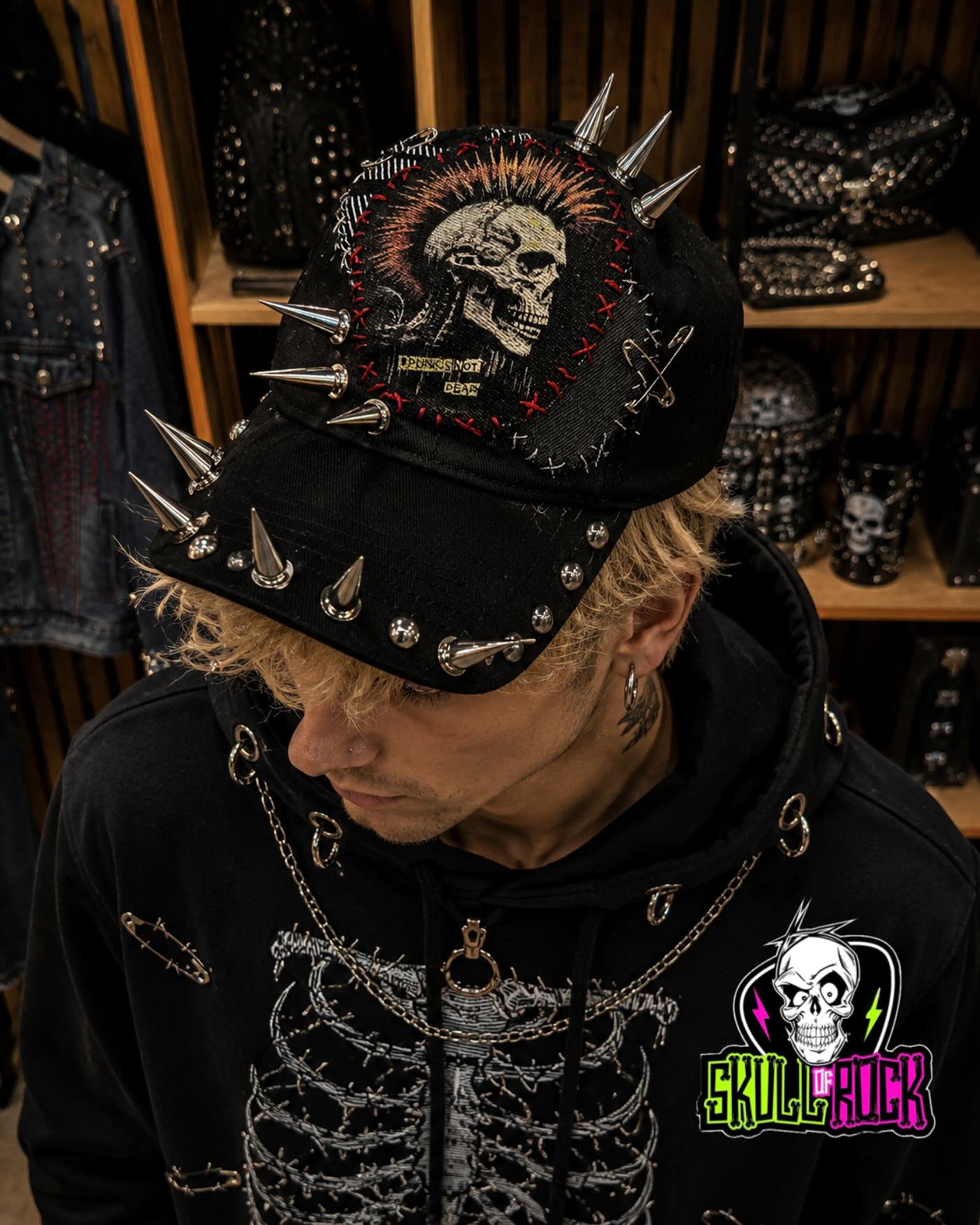 Jockey negro con puntas, tachas, imperdibles y parche de calavera con costuras rojas.