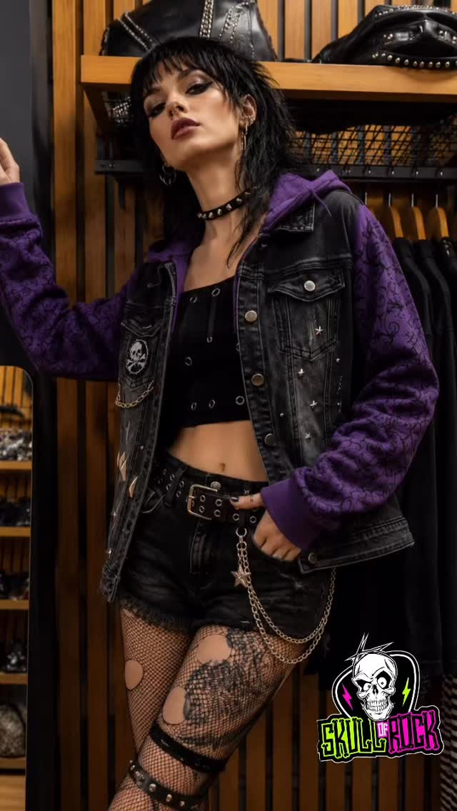 Chaqueta de mezclilla negra con mangas y gorro en tonos púrpura, cadenas y detalles metálicos.